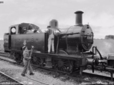 Jinty 47493 seen taking on some more unleaded fuel (water) at Cranmore West Halt, with fireman Pat Goodfellow inspecting the water